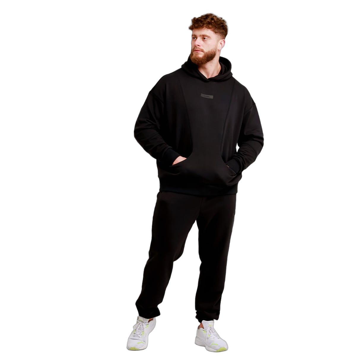 Mann in schwarzer Jogginghose und Kapuzenpullover mit Händen in den Taschen.