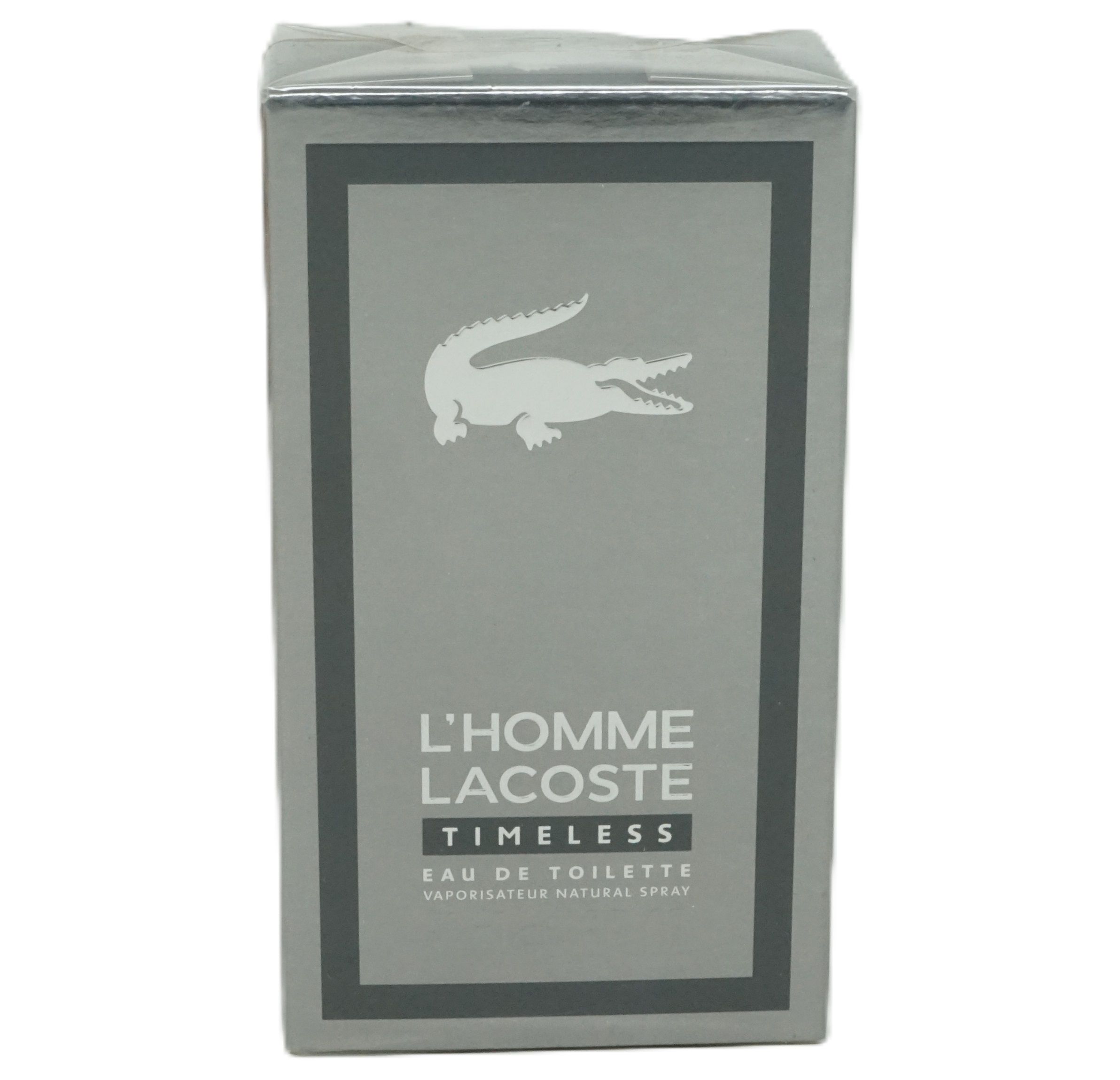 Graue rechteckige Verpackung. Weißes Krokodil-Logo. Schriftzug: L'HOMME LACOSTE TIMELESS Eau de Toilette.
