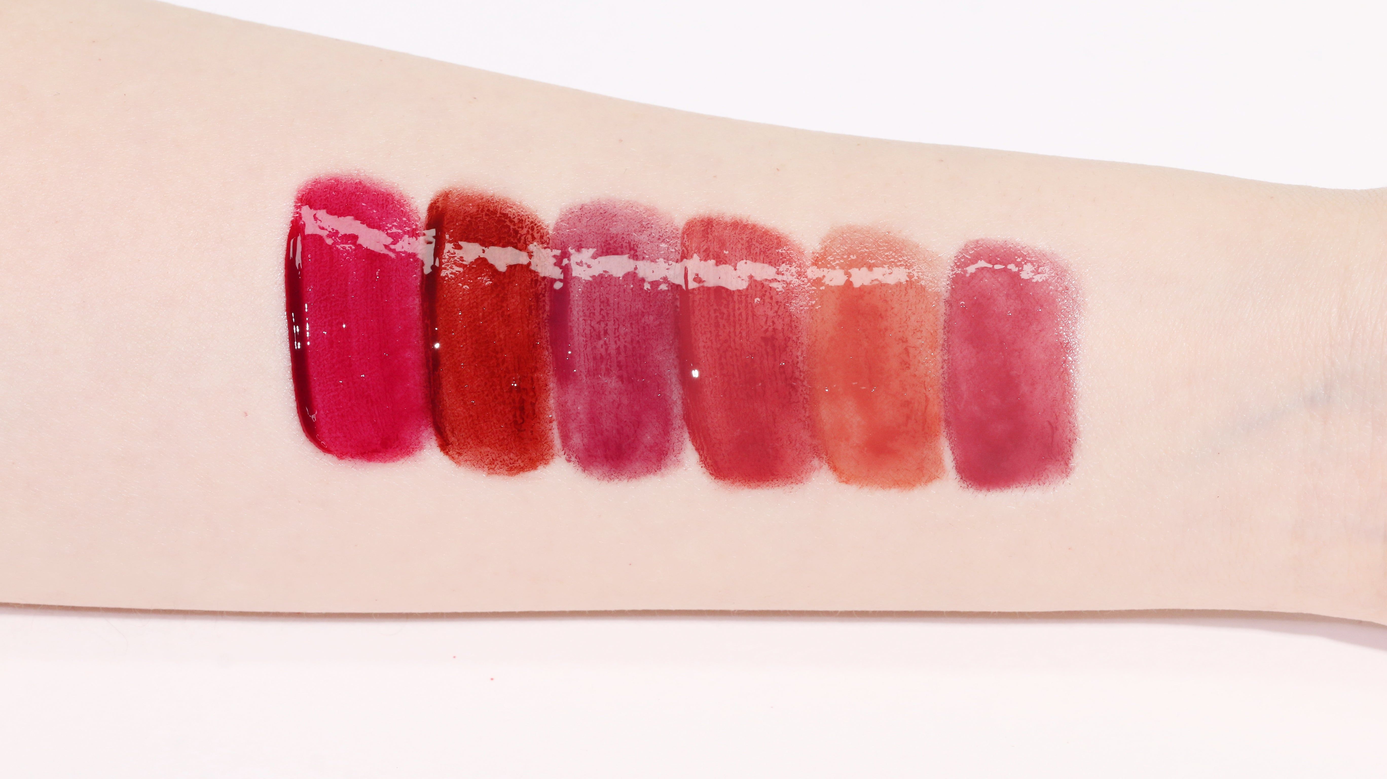 Arm mit sechs Lip Tint-Farbmustern. Verschiedene Rottöne.