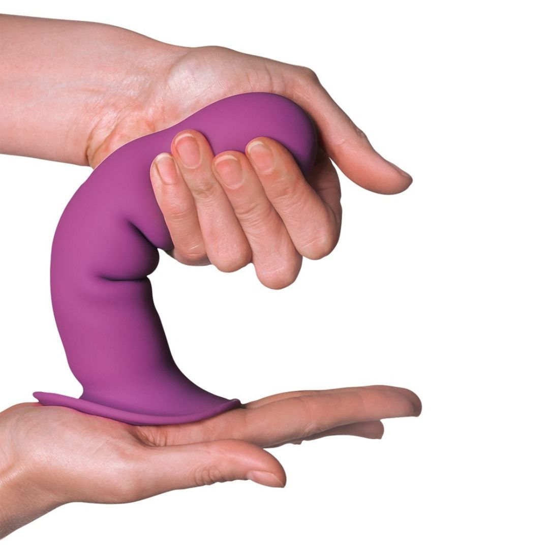 Lila Vibrator in Händen gehalten. Geformt mit gewelltem Schaft und Saugfuß. Aus Silikon.