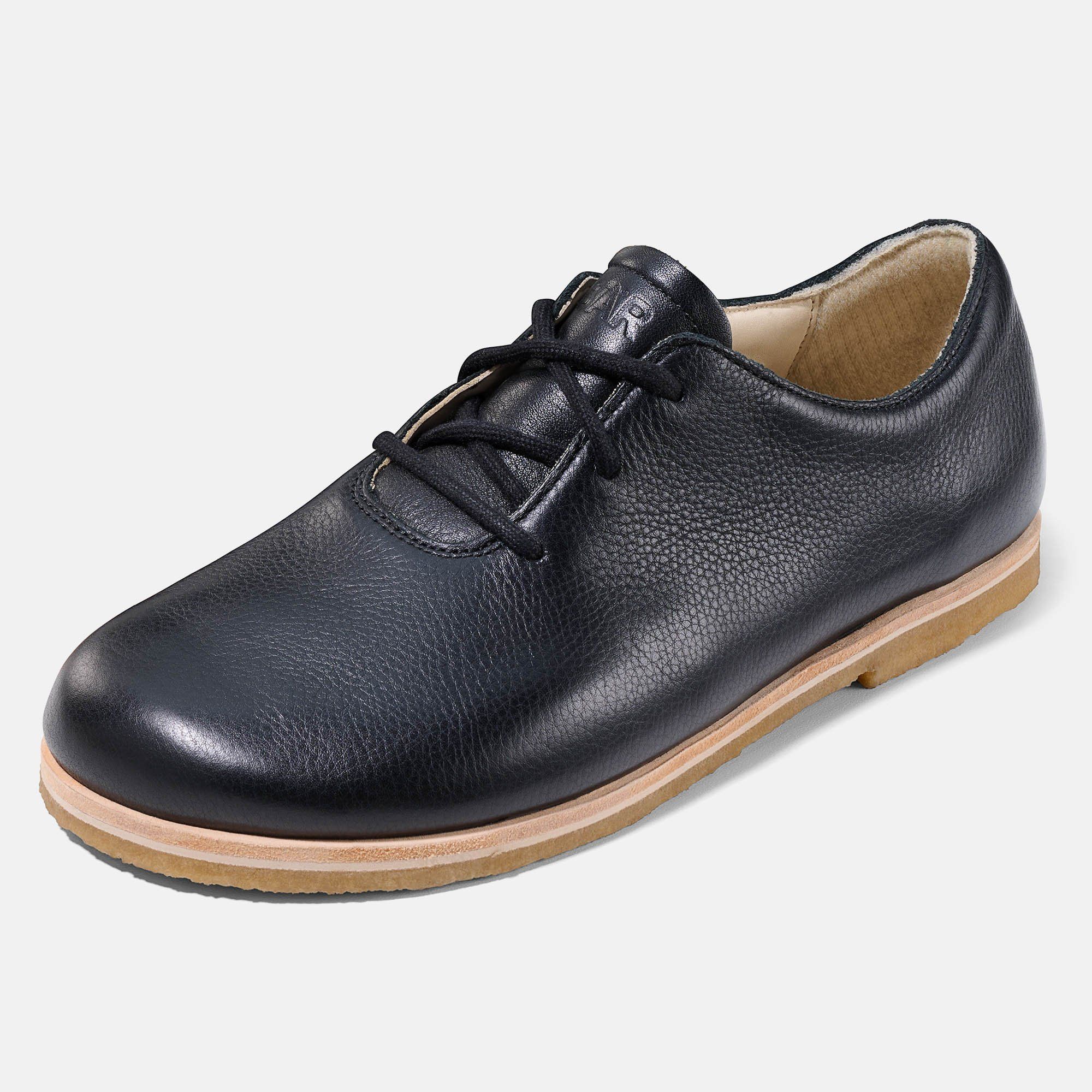 Schwarzer Lederschnürschuh. Helle Sohle. Schuh schräg gestellt.