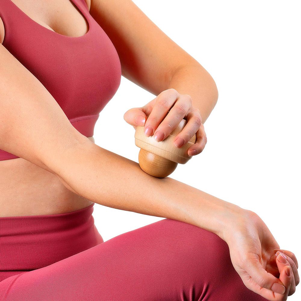 Person verwendet Holz-Massageroller am Arm. Besteht aus einer Kugel und einer Halterung. Natürliches Holz.