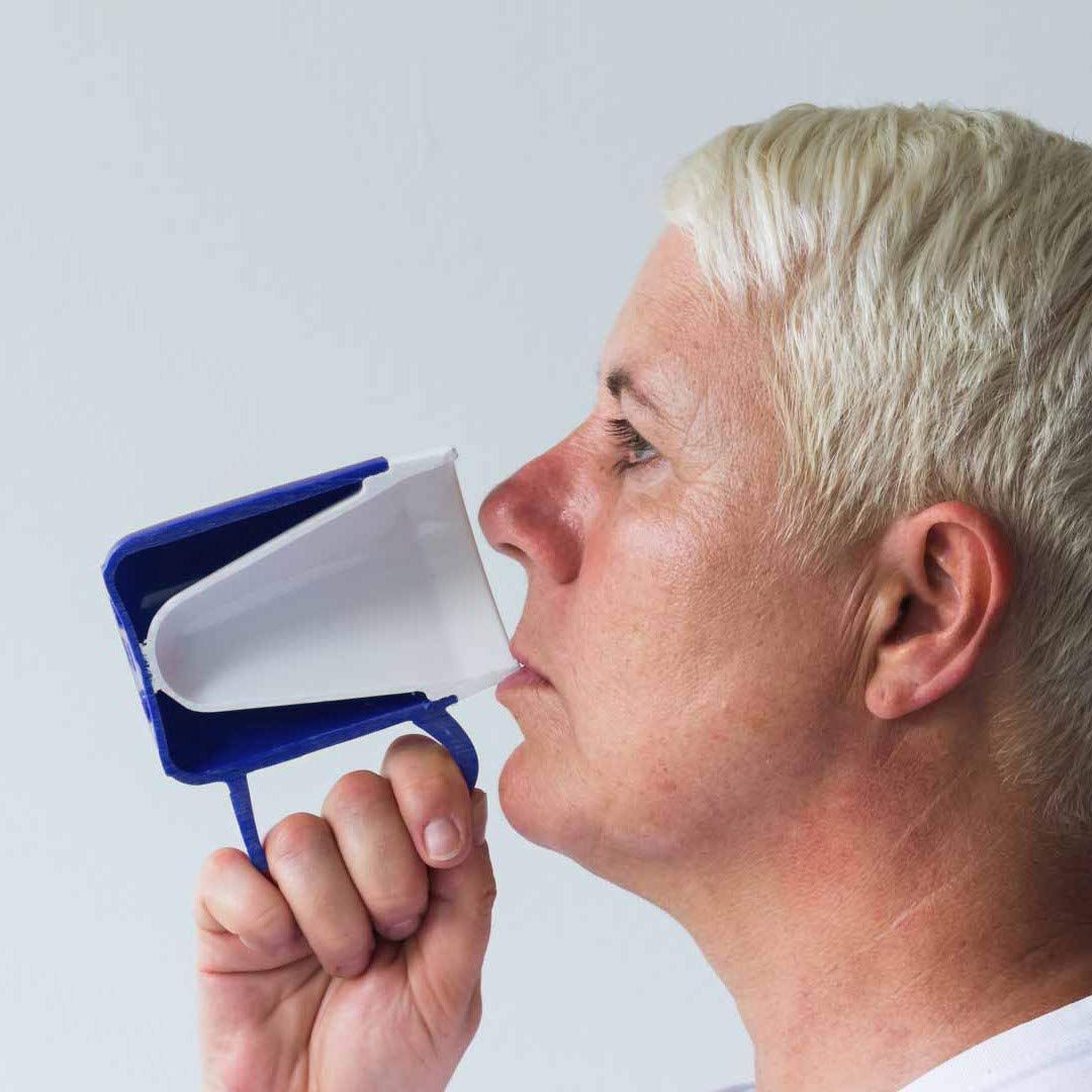 Person trinkt aus einem blauen Becher mit weißem Trinkaufsatz. Der Becher wird zum Mund geführt.