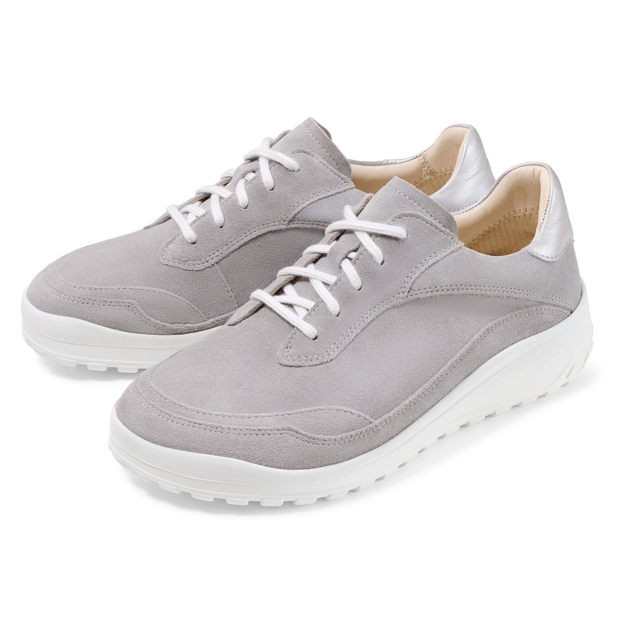 Zwei graue Schnürschuhe mit weißer Sohle. Silberfarbene Akzente an der Ferse. Hellgraues Wildleder-Obermaterial. Schnürsenkel.