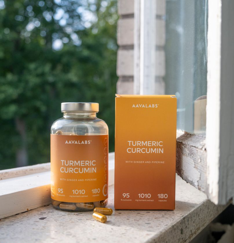 Glasflasche und Karton mit Kapseln. Aufschrift: Turmeric Curcumin, mit Ingwer und Piperin. 180 Kapseln.
