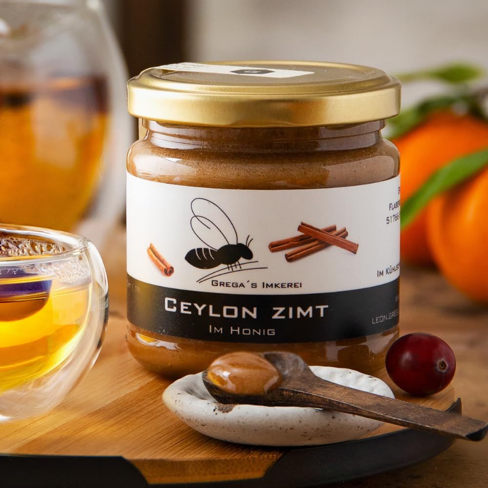 Glas Ceylon Zimt Honig auf einem Holzbrett mit Tee und Beeren.
