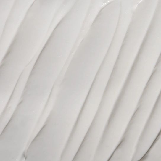 Nahaufnahme von weißer Creme mit wellenförmiger Textur. Die Creme ist glatt und glänzend.