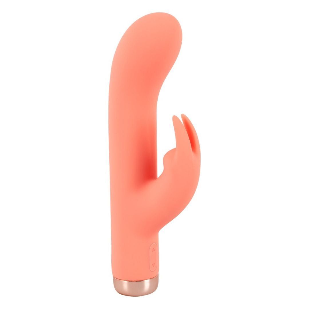 Korallenfarbener Minivibrator mit Hasenohren-Design. Goldfarbener Sockel. Auf weißem Hintergrund.