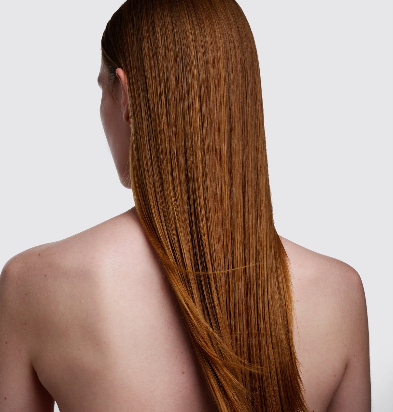 Rückansicht einer Person mit langen, roten Haaren. Die Haare sind glatt und fallen gerade nach unten.