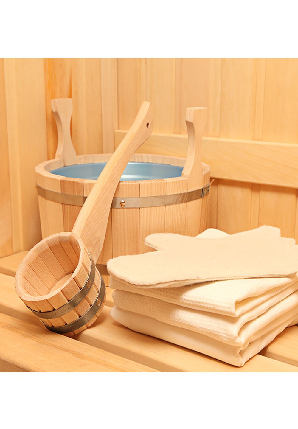 Sauna-Zubehör: Holzeimer mit Kelle, gefüllt mit Wasser, und gestapelte Handtücher.