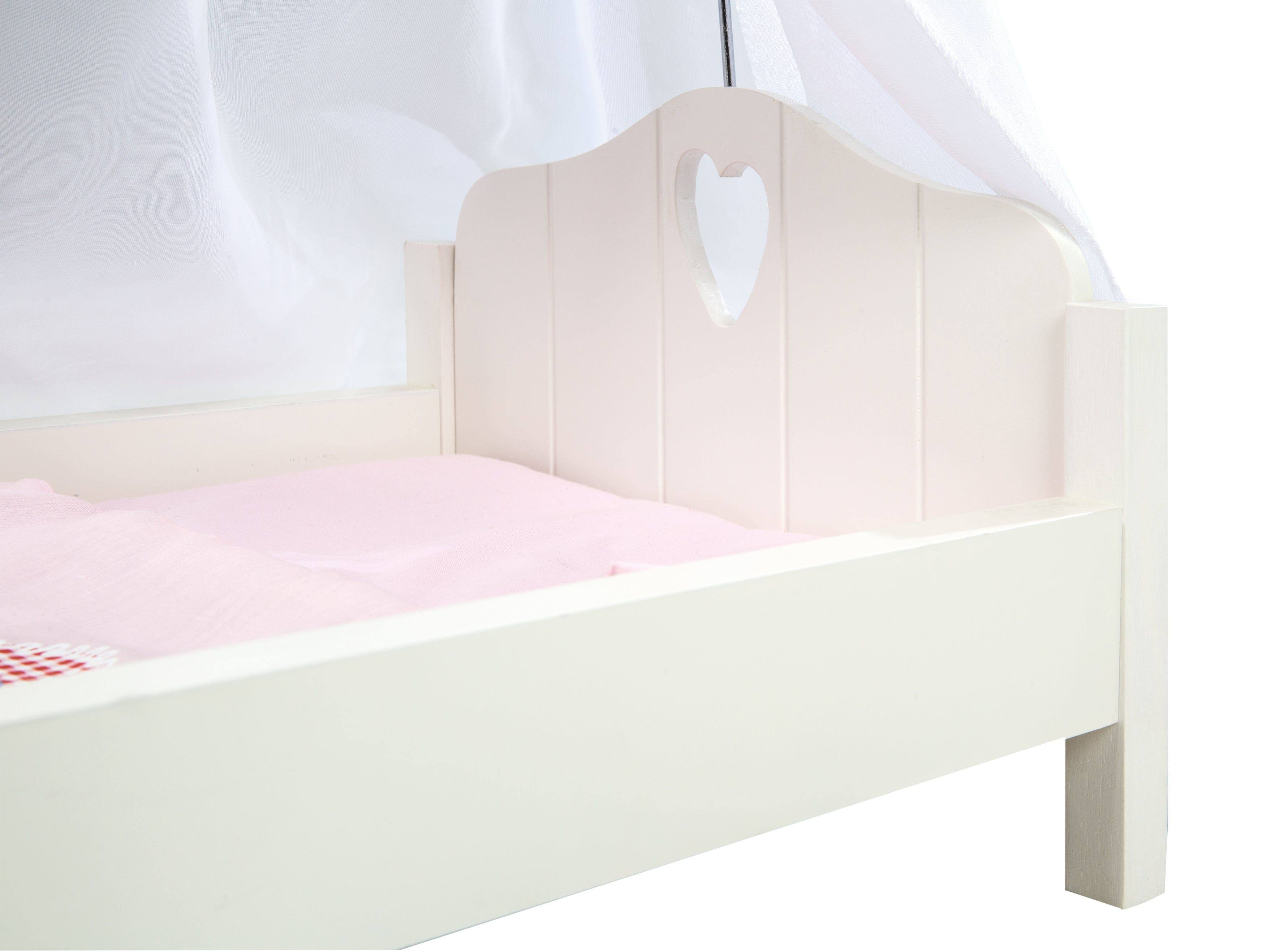 Weißes Puppenbett mit herzförmiger Aussparung im Kopfteil. Rosa Bettwäsche. Vor weißem Hintergrund.