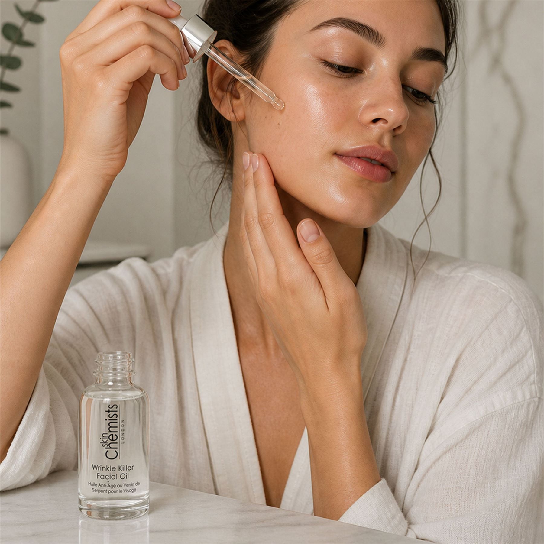Frau mit SkinChemists Faltenbekämpfendes Anti-Aging-Gesichtsöl in Pipettenflasche.