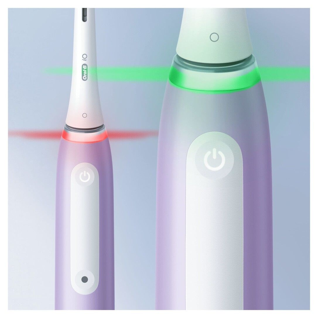 Nahaufnahme einer elektrischen Zahnbürste. Leuchtende Ringe in Grün und Rot. Ein-Aus-Taste. Weißer Bürstenkopf.