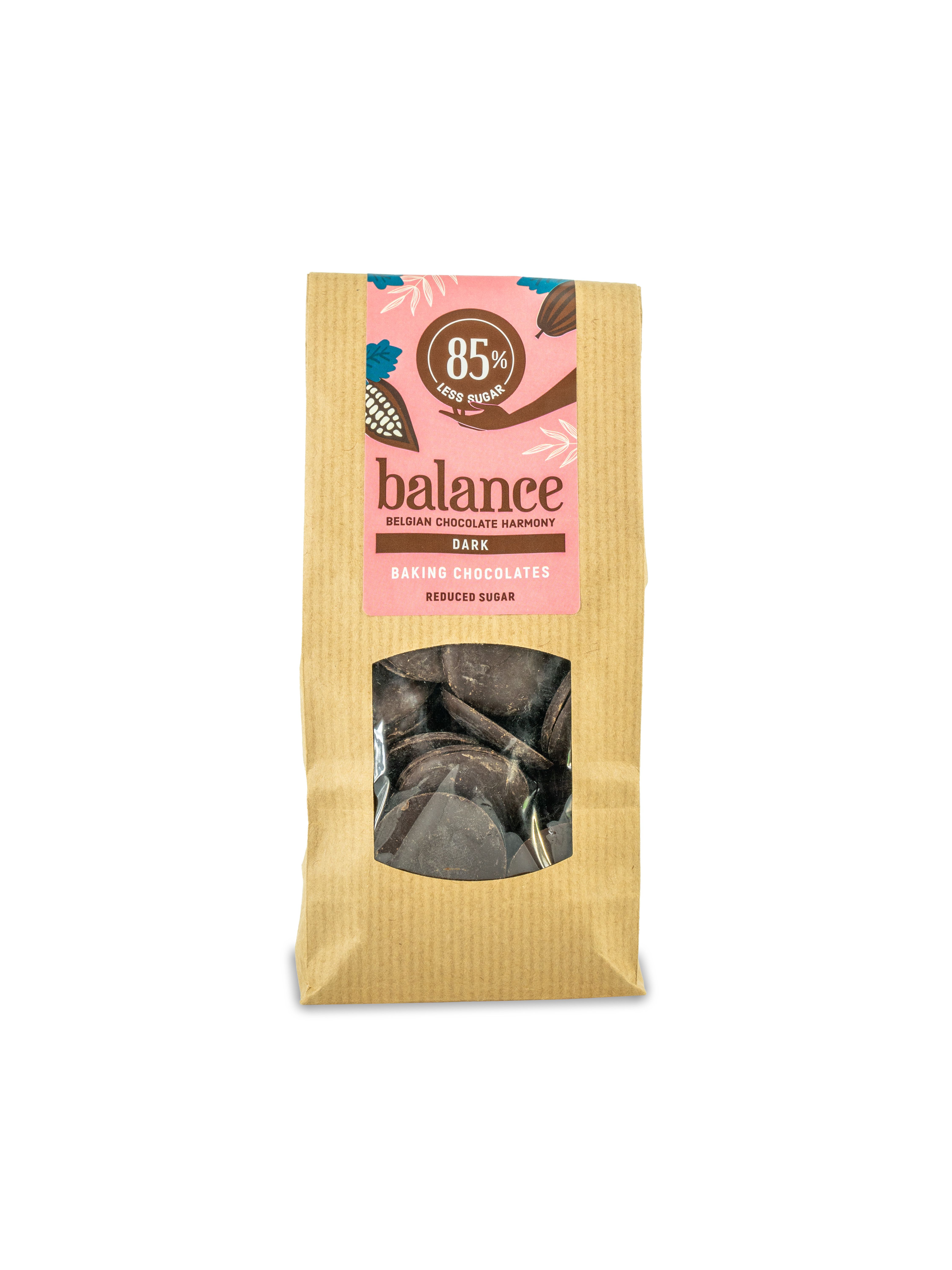 Braune Papiertüte mit Sichtfenster. Rosa Etikett mit "balance" und "85% Kakao". Dunkle Backschokoladenstücke sichtbar.
