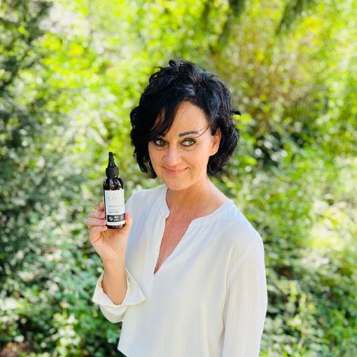 Frau hält eine braune Flasche mit Sprühkopf. Text: Regenerating Hair Tonic.
