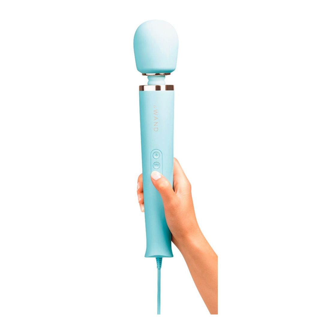 Himmelblauer Wand-Massager in Hand gehalten. Goldfarbener Ring am Kopf. Drei Knöpfe am Griff. Marke: Le Wand.