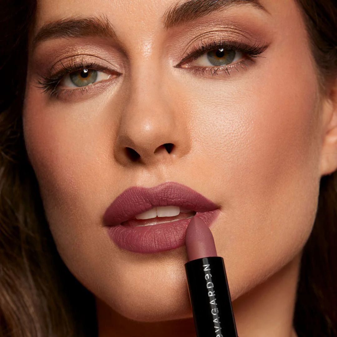 Frau trägt Lippenstift. Schwarze Hülse mit weißem Schriftzug. Lippen in Rosa.