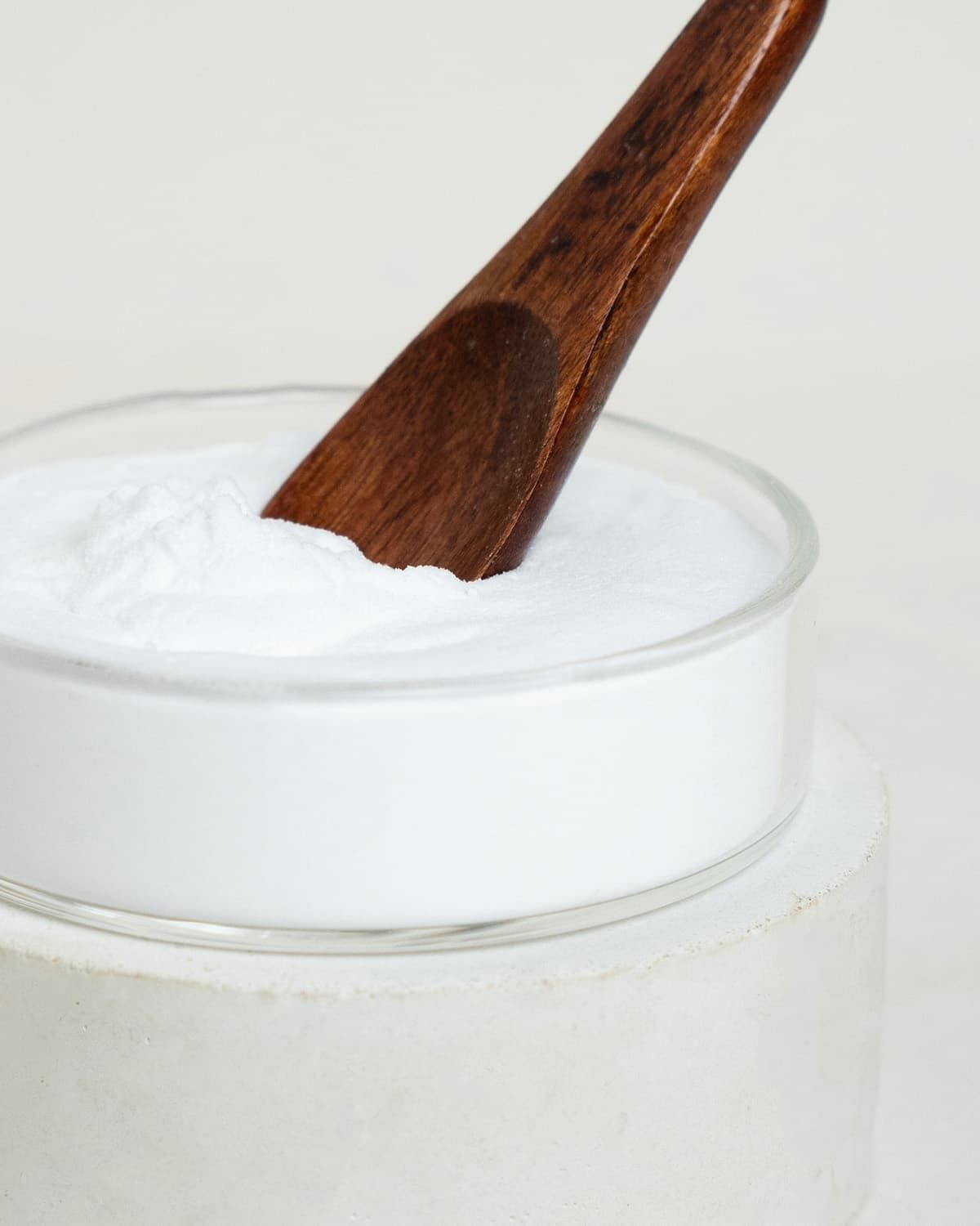 Nahaufnahme von Inositol-Pulver in einer Glasschale mit einem Holzspatel.