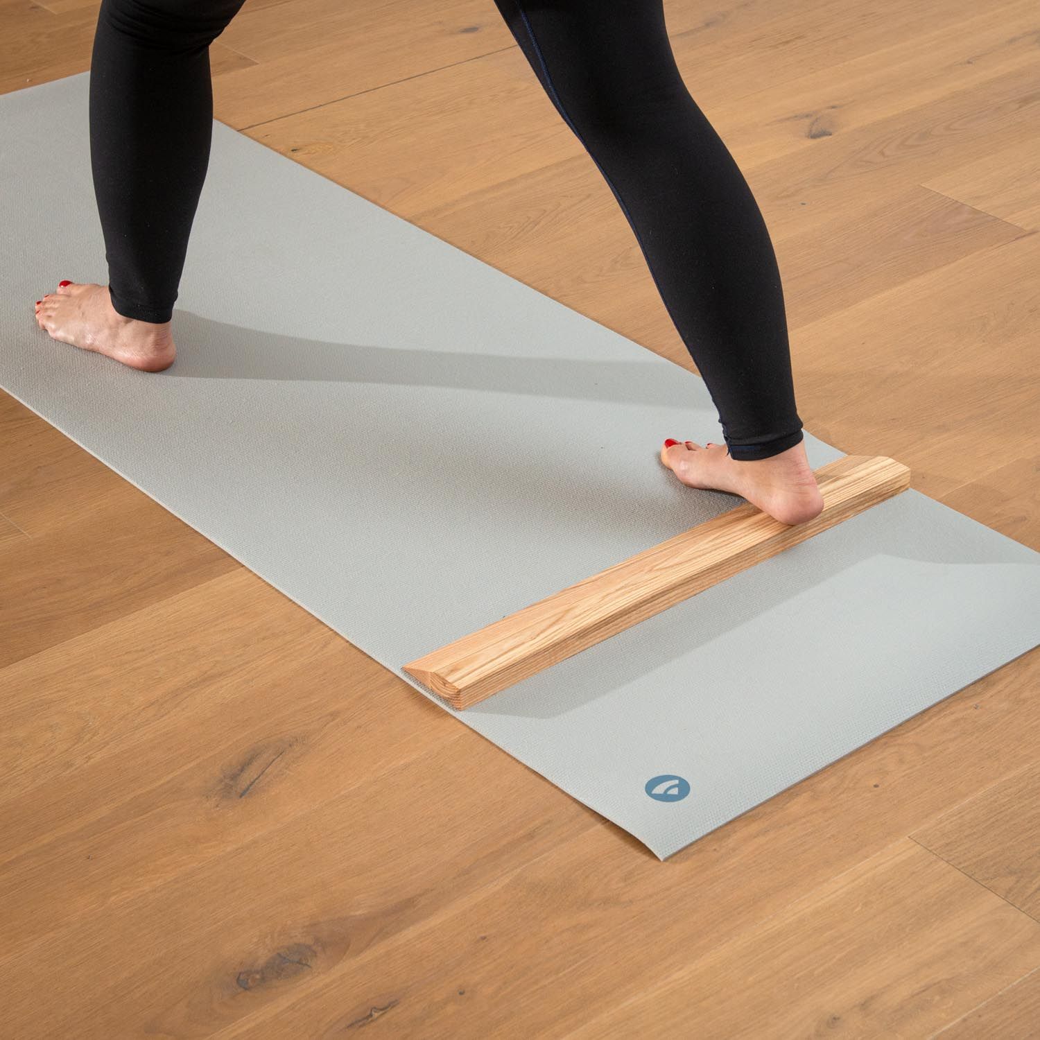Person mit Handstandplanke auf Yogamatte. Hellbraunes Holz. Graue Matte. Person in Yoga-Position.