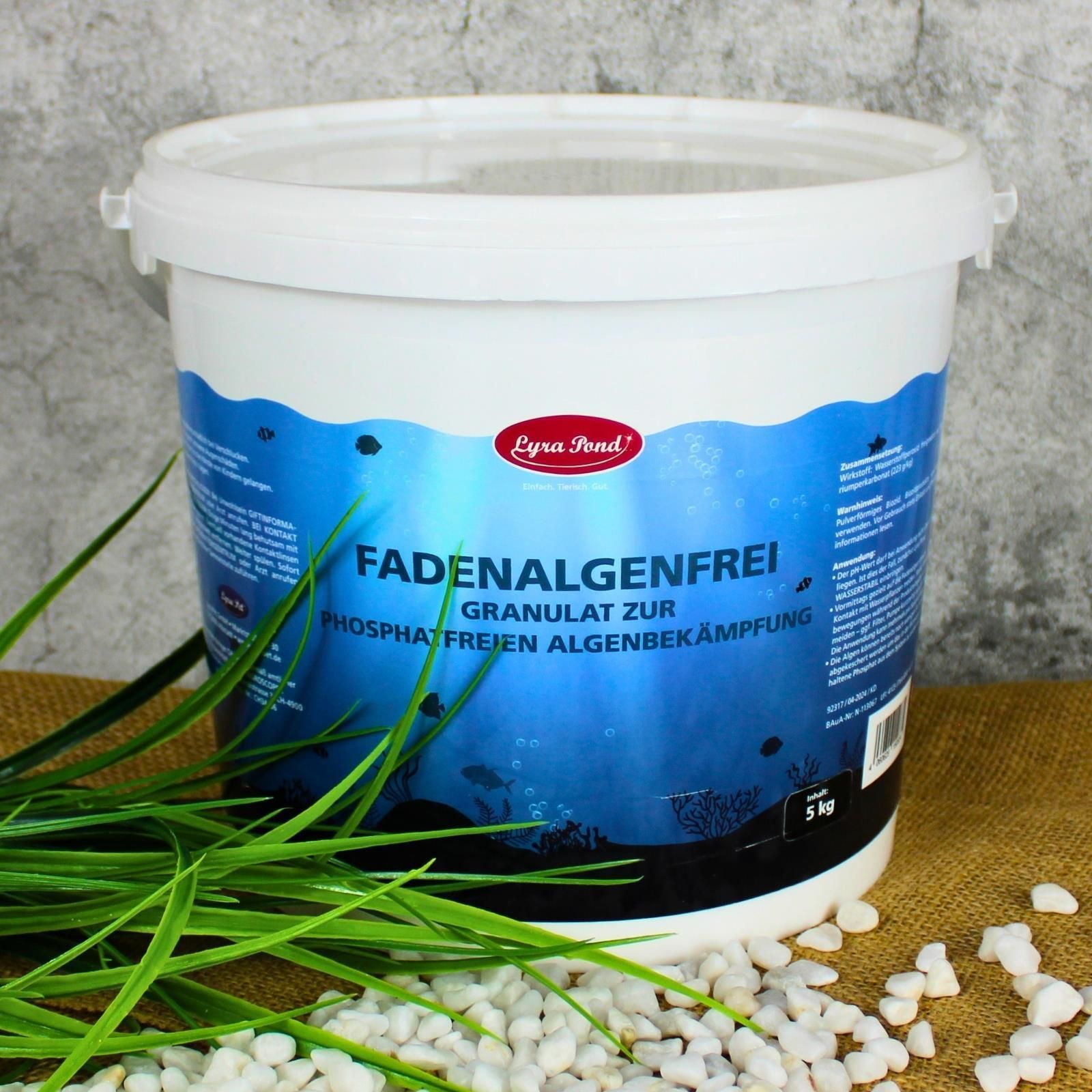Lyra Pond Fadenalgenfrei Granulat Eimer neben Gras und Steinen.