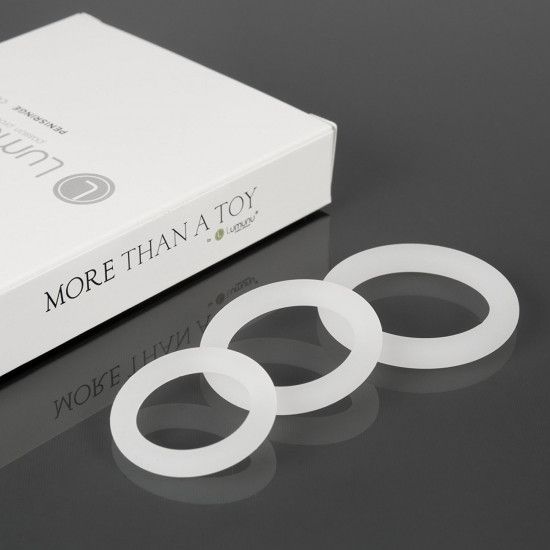 Drei weiße Silikon-Penisringe. Die Ringe liegen vor einer weißen Schachtel mit der Aufschrift "MORE THAN A TOY".