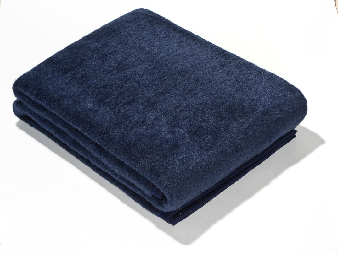 Gefaltete, dunkelblaue Wolldecke. Weiches Material, rechteckige Form. Auf weißem Hintergrund.