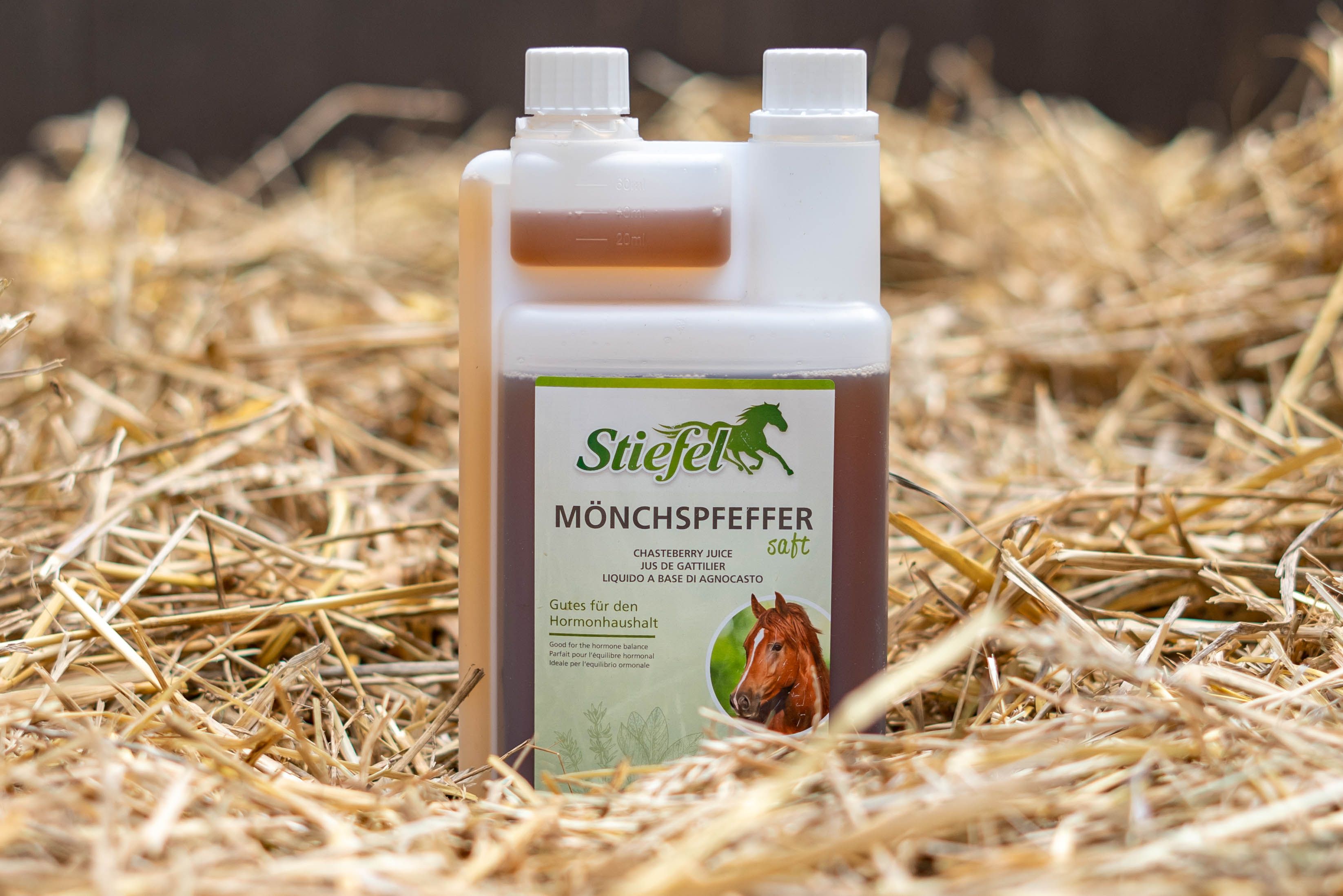 Flasche Stiefel Mönchspfeffersaft auf Stroh. Durchsichtige Flasche mit brauner Flüssigkeit und weißem Deckel.