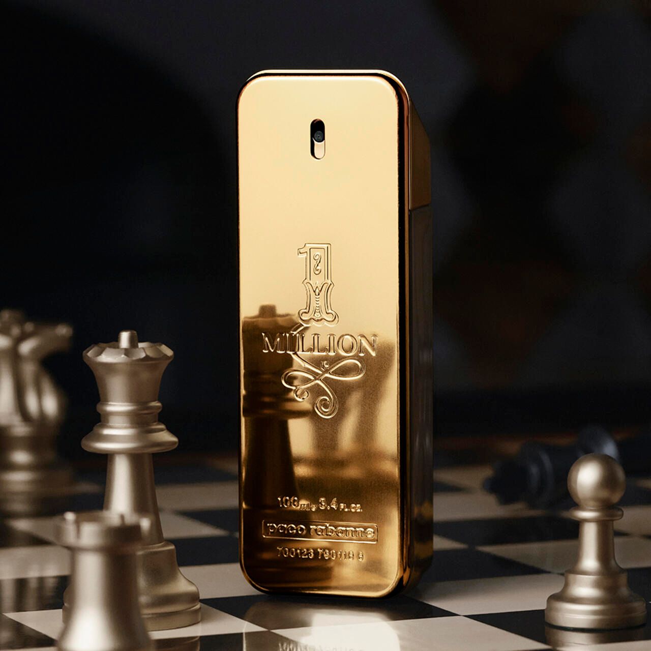 Goldfarbener Flakon "1 Million" auf Schachbrett mit Schachfiguren. Eckige Form, goldene Farbe.