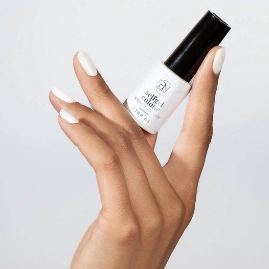 Hand mit weiß lackierten Nägeln, hält eine Flasche Nagellack. Auf der Flasche steht "PN selfgel colour N001 fresh milk STEP 03".