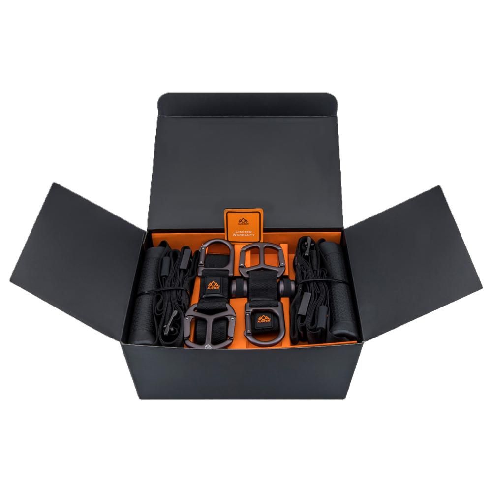 Schwarze Box mit orangefarbenem Innenraum. Enthält schwarze Gurte, Griffe und Zubehör. Orangefarbenes Logo.