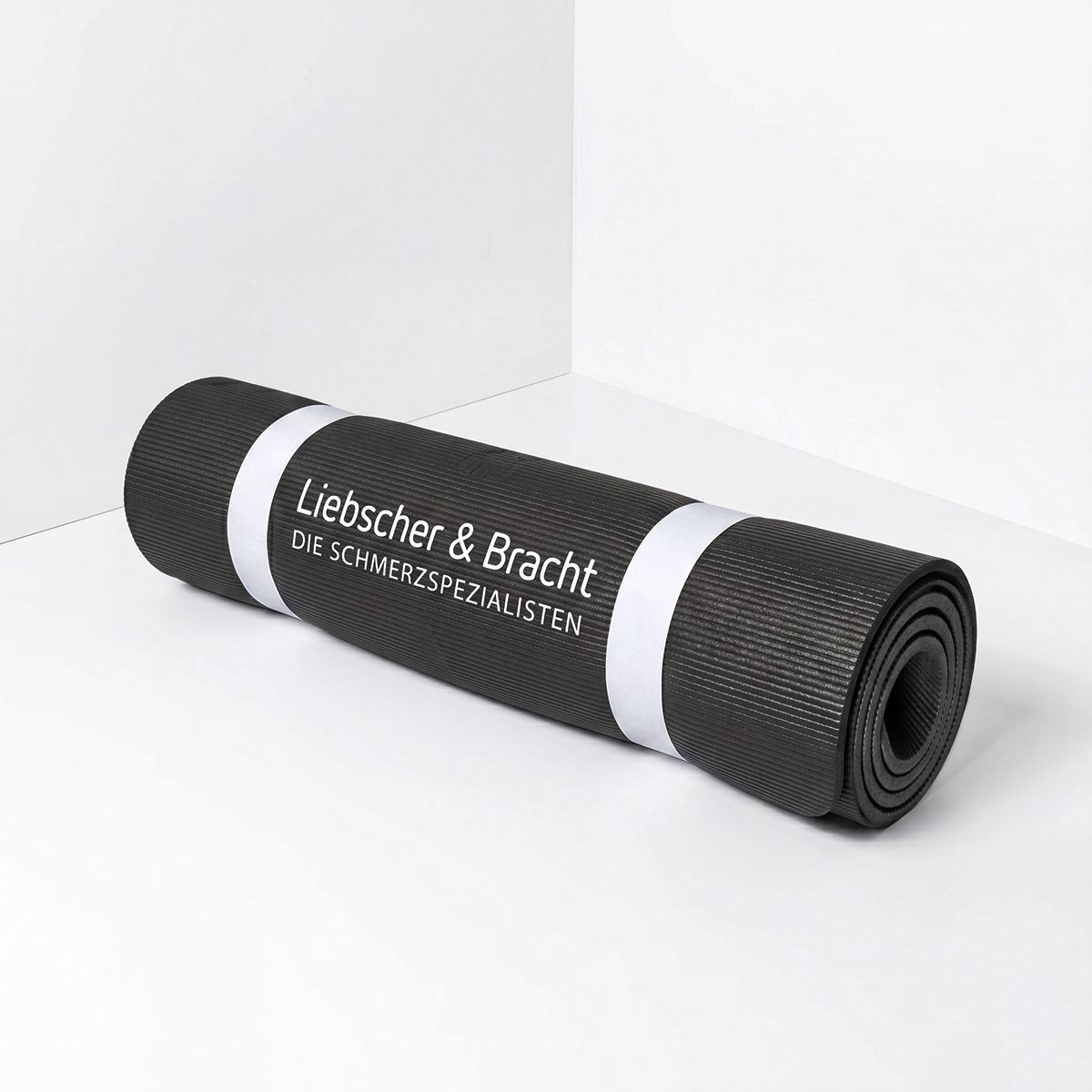 Gerollte schwarze Matte mit weißem Band und Logo.
