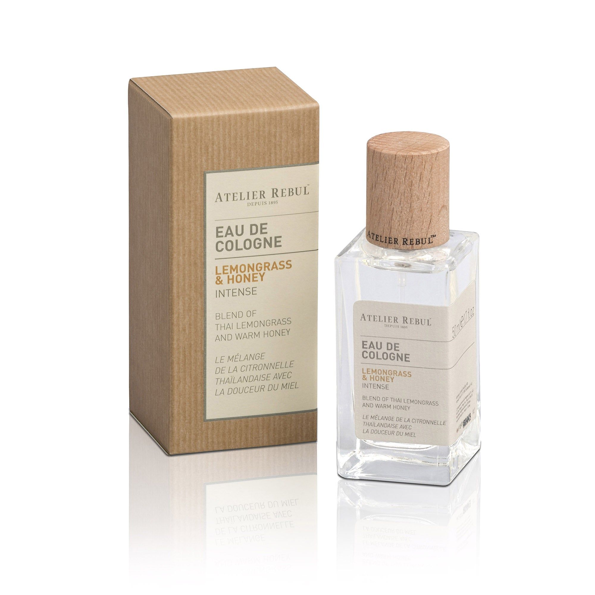 Eine Flasche Eau de Cologne mit Holzverschluss und Kartonverpackung. Aufschrift: Atelier Rebul, Eau de Cologne, Lemongrass & Honey Intense.