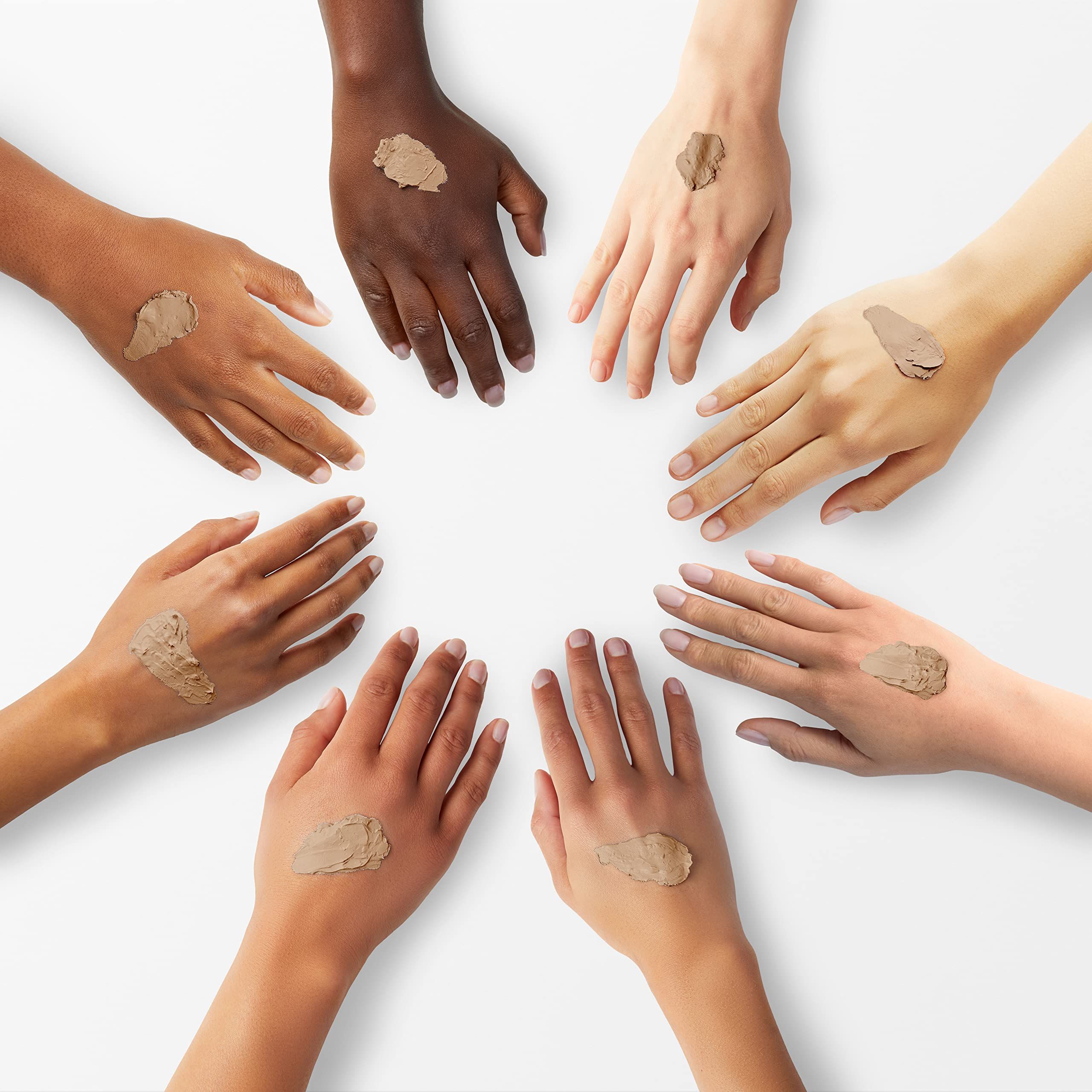 Sieben Hände mit unterschiedlichen Hauttönen, jeweils mit einem Klecks Concealer auf dem Handrücken.