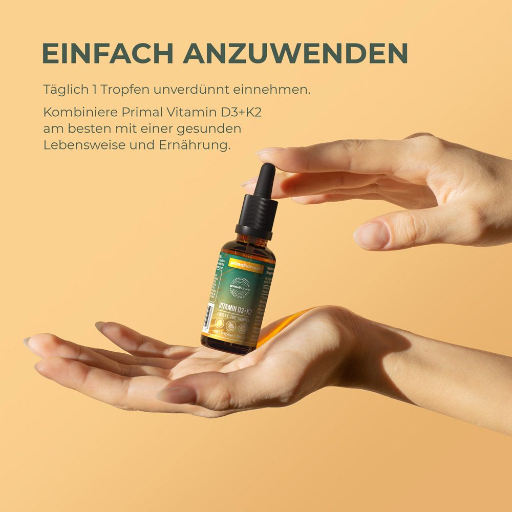 Hände halten eine braune Glasflasche mit schwarzem Tropfer. Etikett mit Produktinformationen. Gelber Hintergrund. Text: Vitamin D3+K2.