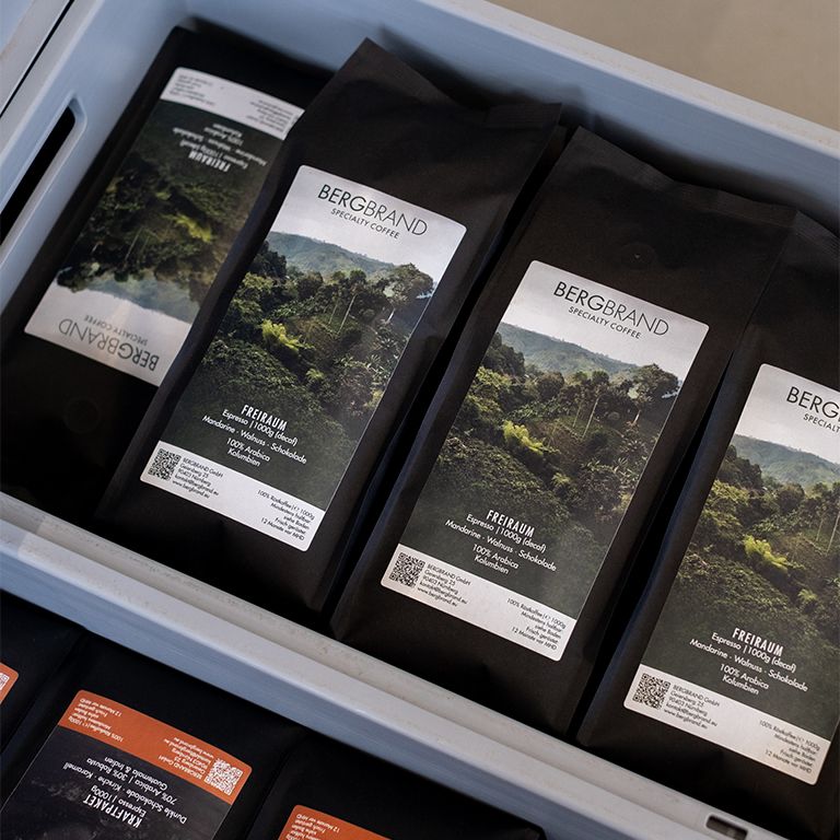 Mehrere schwarze Beutel mit BERGBRAND-Logo in einer Kiste.