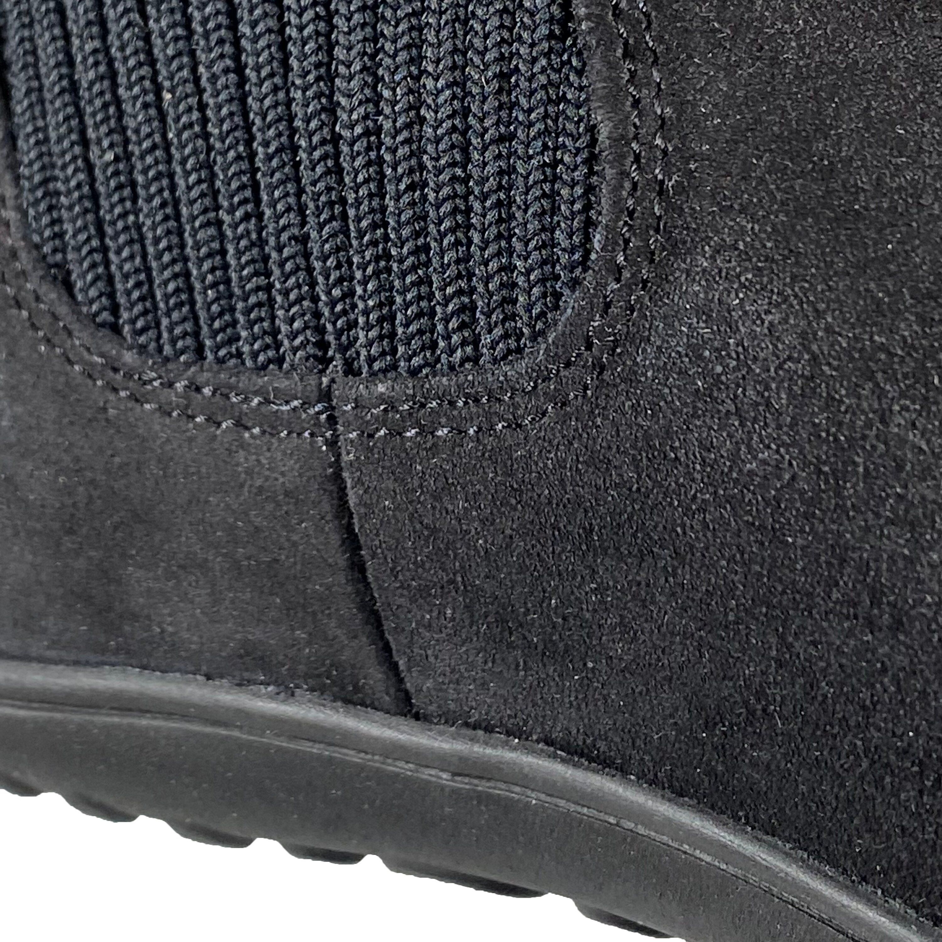Detail der schwarzen Stiefelette. Wildleder, gerippter Schaft. Naht am Übergang. Schwarze Sohle.