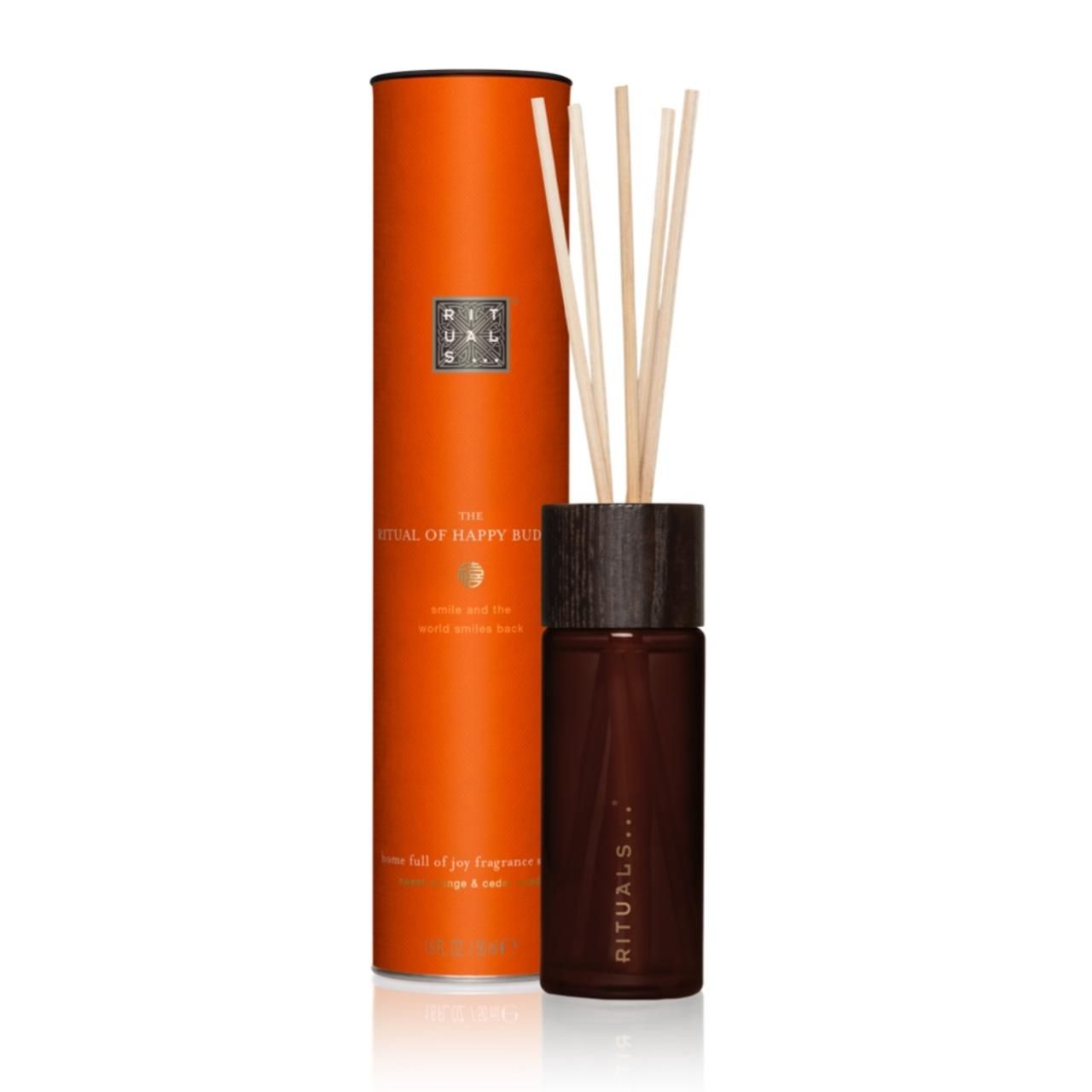 Braune Glasflasche mit Holzdeckel und Stäbchen, neben orangefarbener Verpackung. Text: Rituals, The Ritual of Happy Buddha.