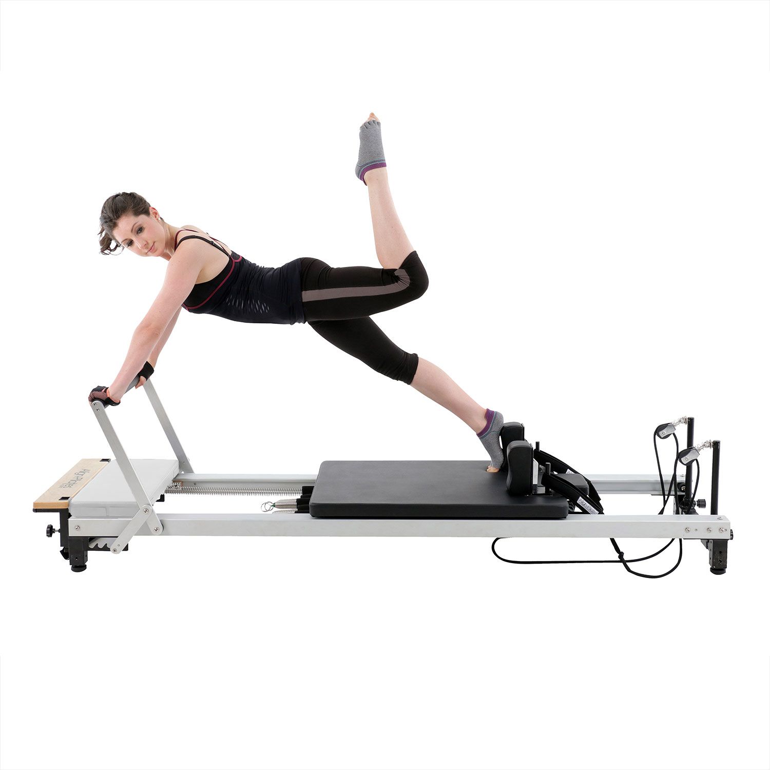 Frau auf Pilates-Gerät. Sie stützt sich auf die Hände, ein Bein gestreckt nach oben.