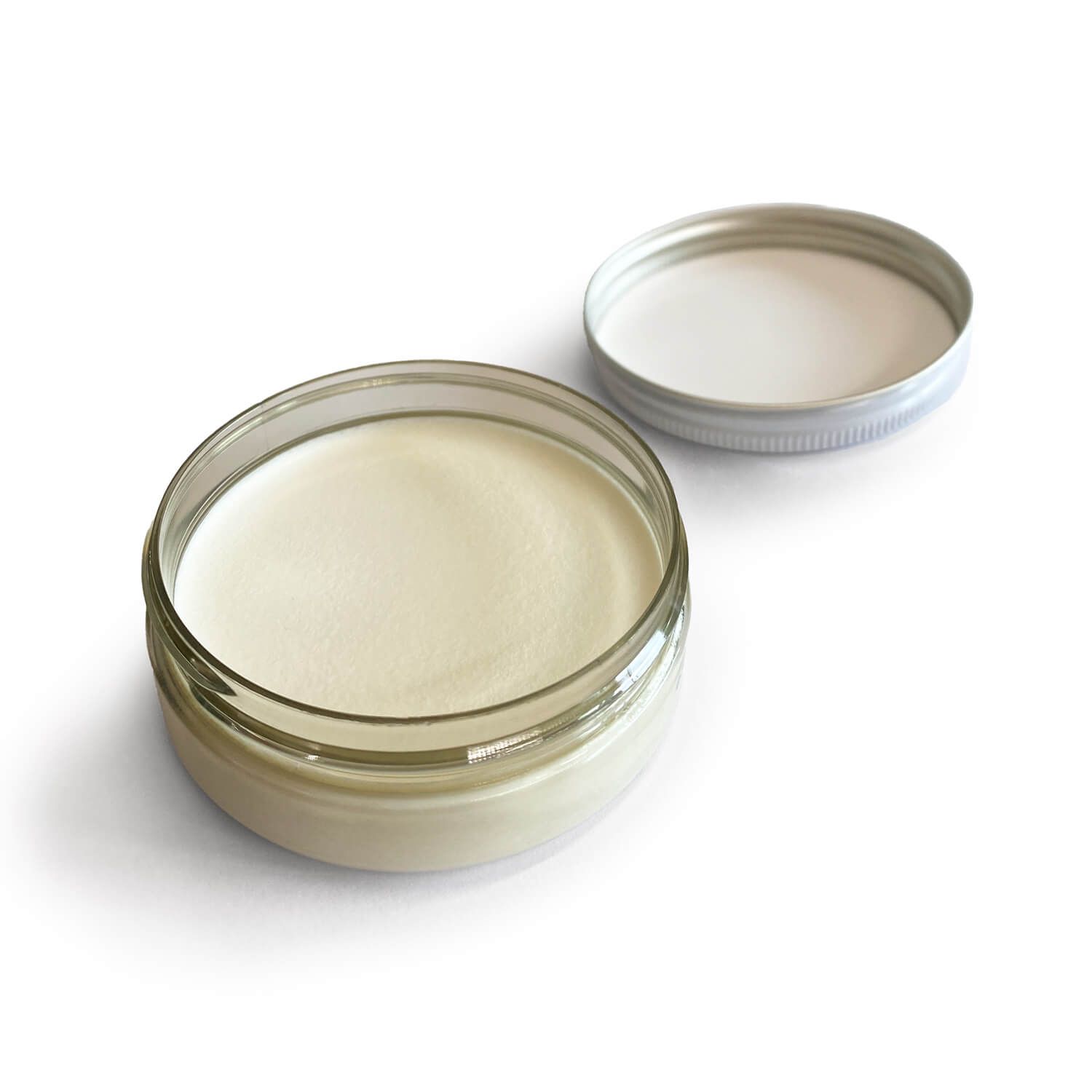 Offenes Glas mit Creme. Deckel daneben. Creme hell und glatt.