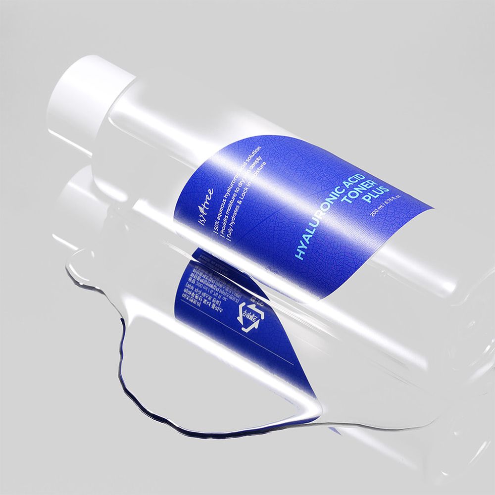 Transparente Flasche mit blauem Etikett. Aufschrift: Hyaluronic Acid Toner Plus. Flüssigkeit auf glatter Oberfläche.