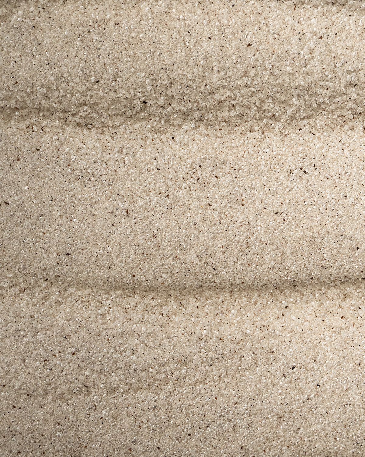 Nahaufnahme von feinem, hellem Sand mit horizontalen Streifen.
