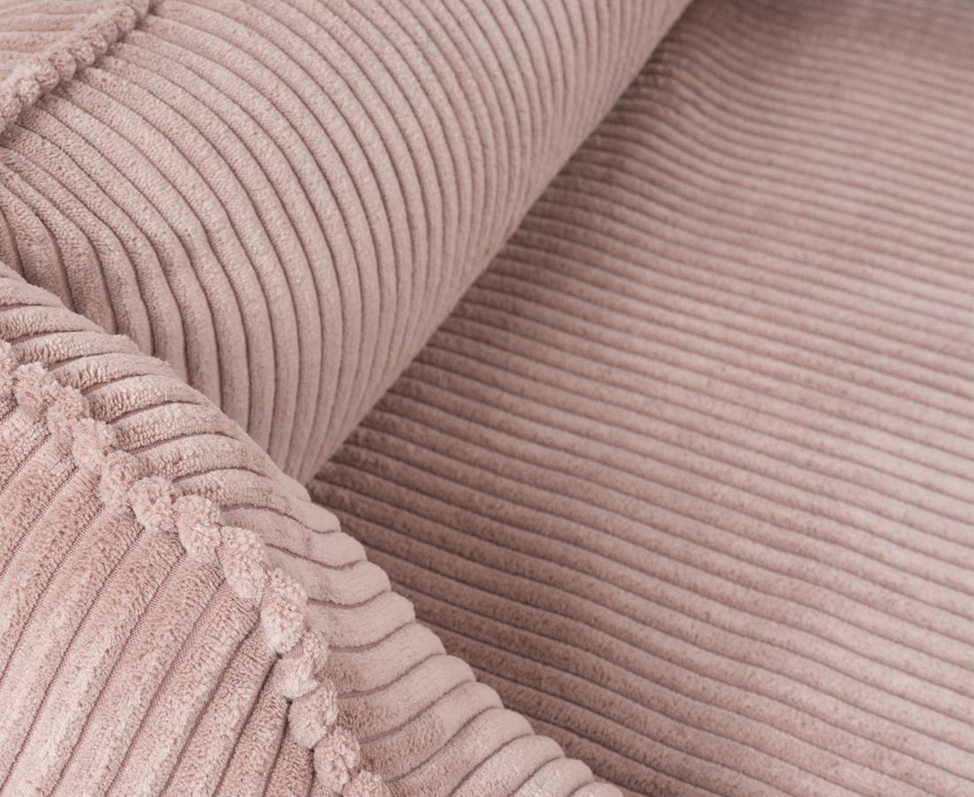 Nahaufnahme des rosa Cord-Stoffes eines orthopädischen Hundebetts. Gerollter Stoff, sichtbare Struktur.