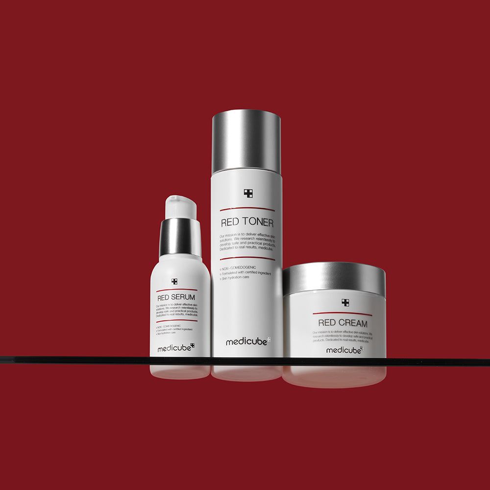 Drei weiße Flaschen auf rotem Hintergrund. Aufschrift "RED SERUM", "RED TONER", "RED CREAM" und "medicube".