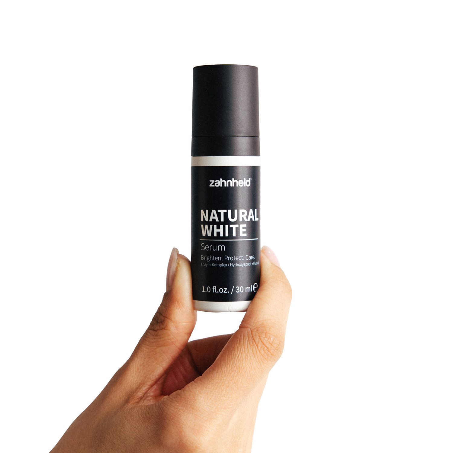 Hand hält Zahnheld Natural White Serum Flasche.