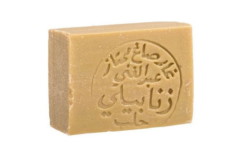 Rechteckige Seife mit arabischer Schrift. Die Seife ist hellbraun und hat eine runde Prägung mit Schriftzeichen.