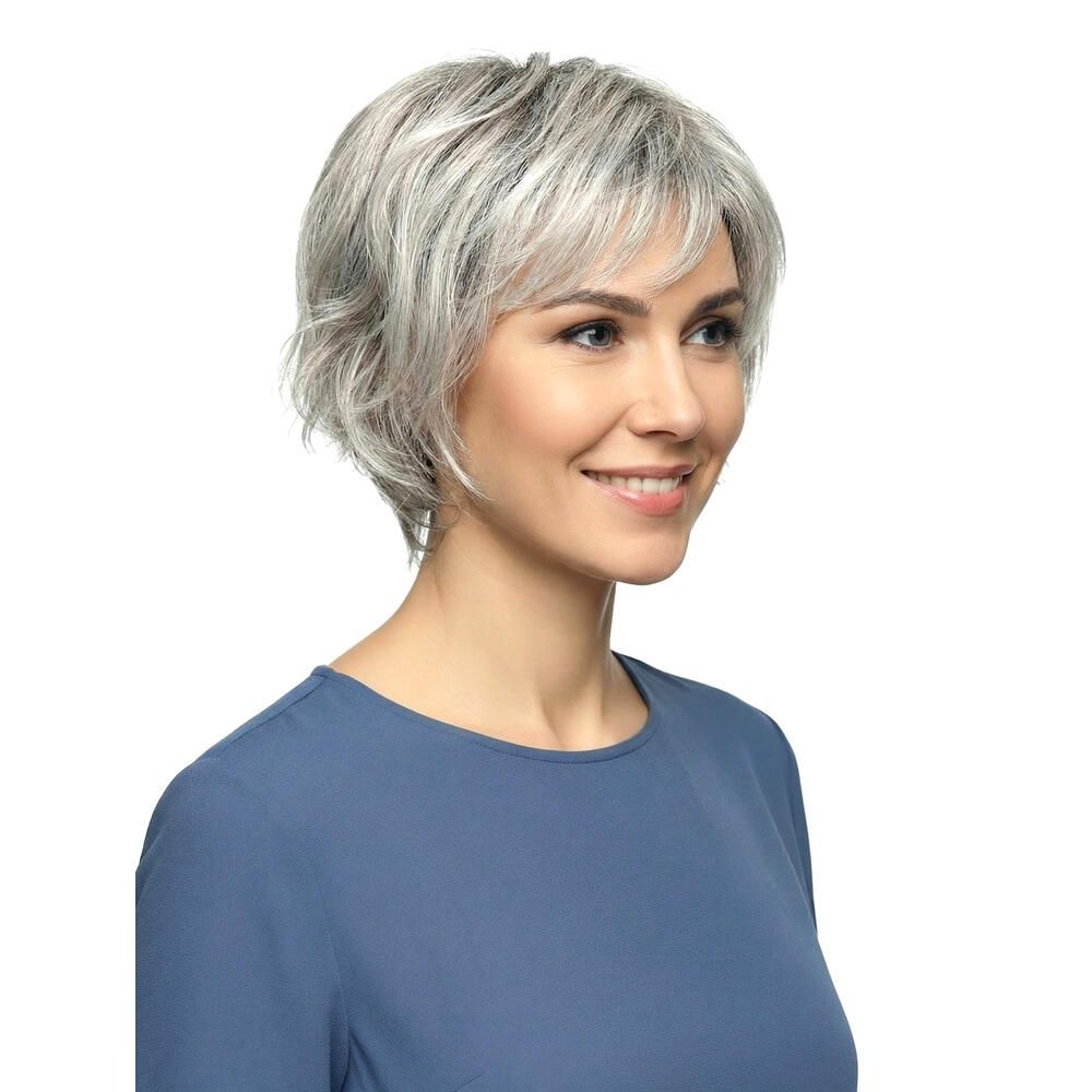 Kurzhaarperücke, grau-meliert, mit Pony, von einer Frau getragen. Die Frau lächelt und trägt ein blaues Oberteil.