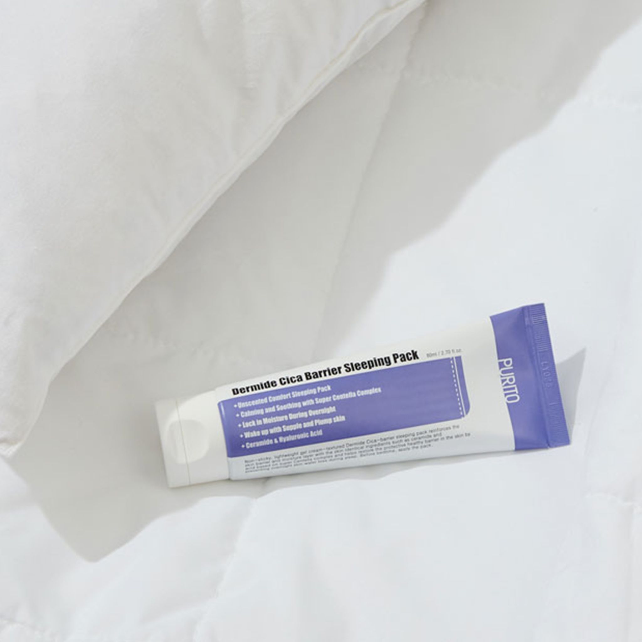 Tube mit Produkt auf weißem Bettbezug. Aufschrift: Dermide Cica Barrier Sleeping Pack.