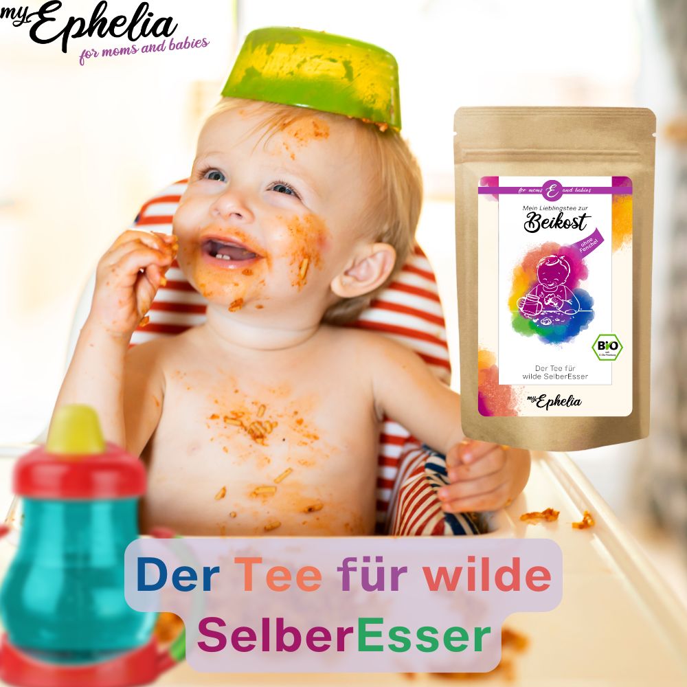 Baby isst und hat Essen im Gesicht. Daneben Teebeutel-Verpackung.