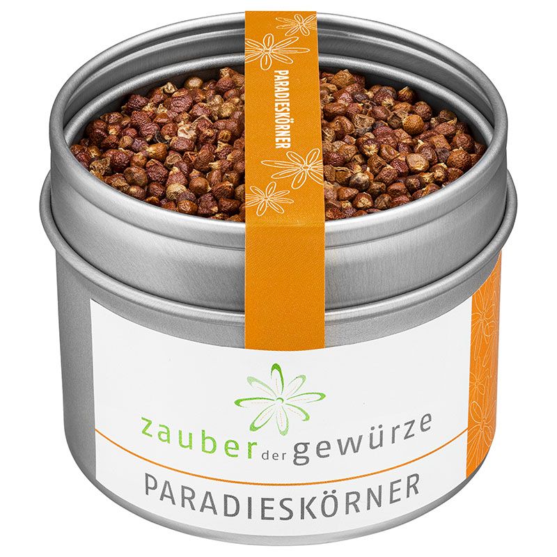 Runde, silberne Dose mit Paradieskörnern. Orangefarbenes Etikett mit Schriftzug. Weißes Etikett mit Logo und Schriftzug.