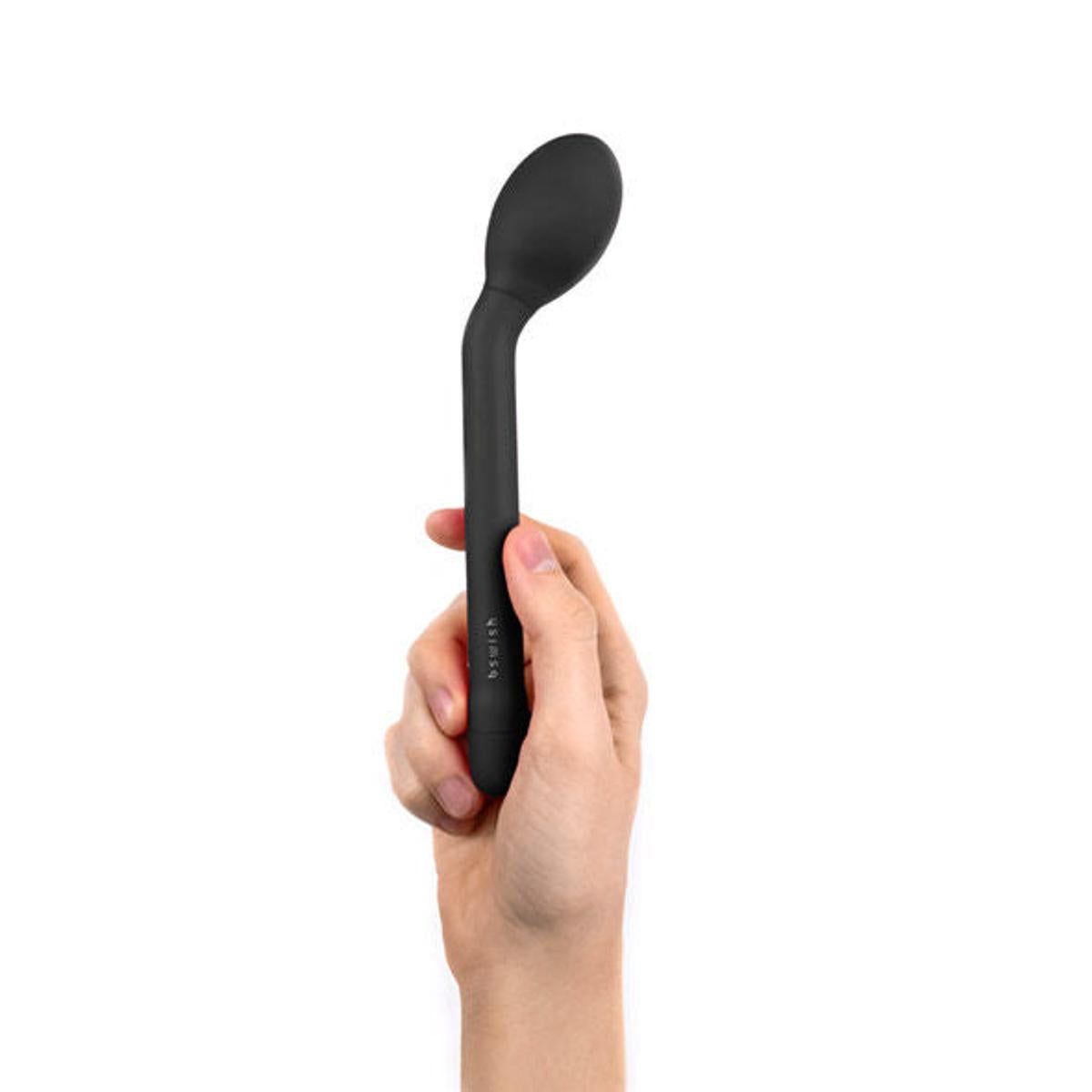 Schwarzer Vibrator in einer Hand gehalten. Der Kopf ist oval, der Griff zylindrisch. Auf dem Griff steht "bswish".